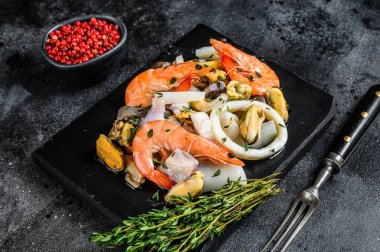 Karides, karides, midye, mürekkep balığı ve ahtapotla taze deniz ürünleri karışımı. Siyah arka plan. Üst görünüm.