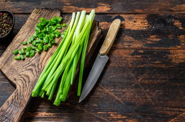 Kesme tahtasındaki soğan soğanlarını kes. Koyu ahşap arka plan. Üst Manzara. Boşluğu kopyala.