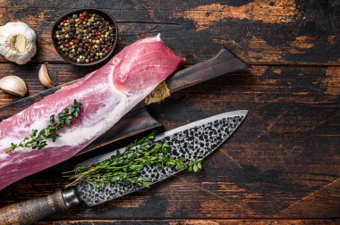 Çiğ domuz filetosu eti ve satırla birlikte kürek tahtasının üzerinde. Koyu ahşap arka plan. Üst Manzara. Boşluğu kopyala.