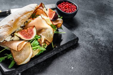 Baget, jambon, incir, roka ve jambonlu sandviç. Siyah arka plan. Üst Manzara. Boşluğu kopyala.