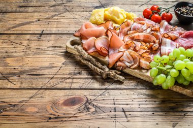 Soğuk, kurutulmuş İtalyan jambonu, jambon, pancetta, parmesanlı pastırma ve üzüm. Ahşap arka plan. Üst Manzara. Boşluğu kopyala.