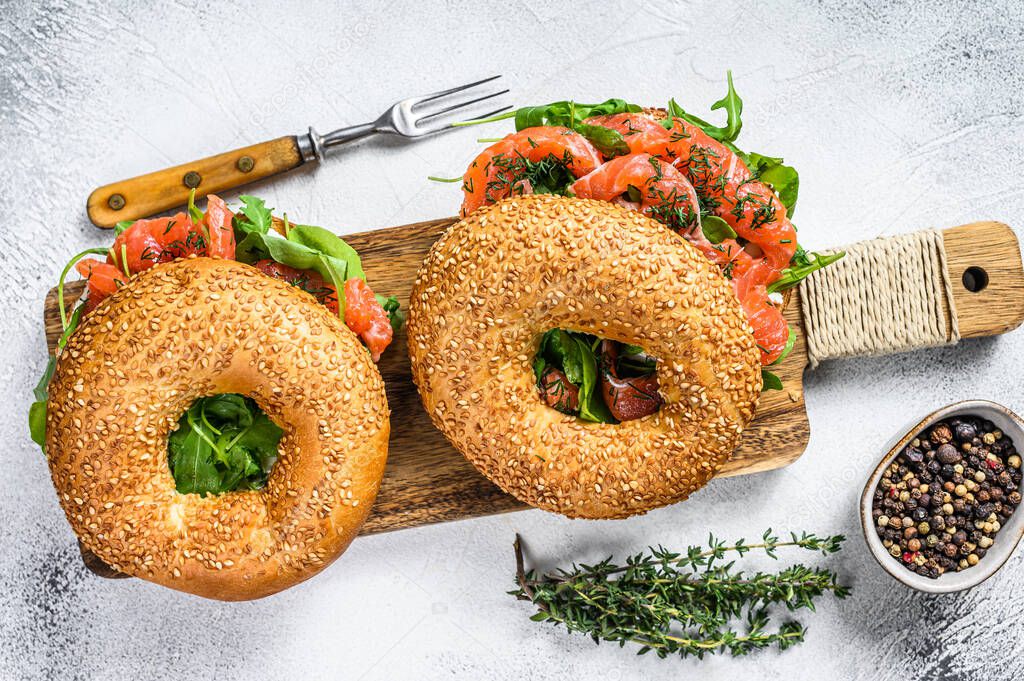 Smoked salmon bagels sandwich with soft cheese and arugula on a cutting board. White background. Top view.