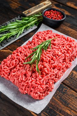 Çiğ et, kasap kağıdı üzerinde kıyma. Koyu ahşap arka plan. Üst görünüm.