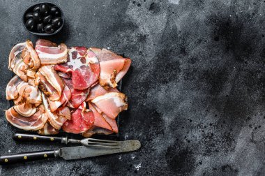 Et antipasto tabağı, pancetta, salam, dilimlenmiş jambon, sosis, jambon, jambon. Siyah arka plan. Üst Manzara. Boşluğu kopyala