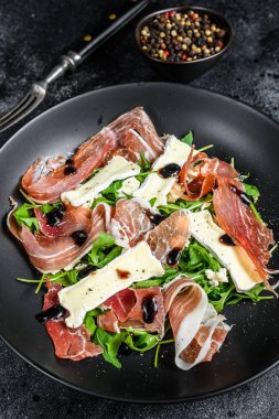 Peynirli peynirli jambonlu jambonlu jambon salatası ve roka. Siyah arka plan. Üst görünüm.