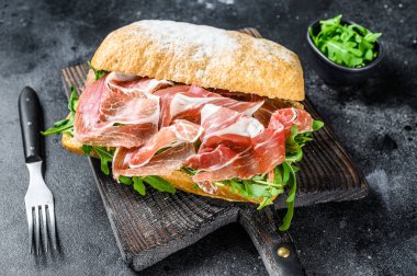 Ciabatta ekmeğinde Iberico Jamon jambonlu sandviç. Siyah arka plan. Üst görünüm.