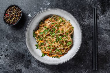 Wok Sıcak Asya selofan eriştesi ve tavuk eti. Siyah arka plan. Üst görünüm.