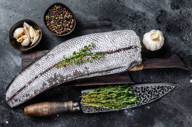 Tahta kesme tahtasındaki çiğ el yapımı makrozor beyaz balığı. Siyah arka plan. Üst görünüm.