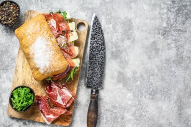 Jambonlu Ciabatta sandviçi, roka ve peynirli peynirli. Gri arka plan. Üst Manzara. Boşluğu kopyala.