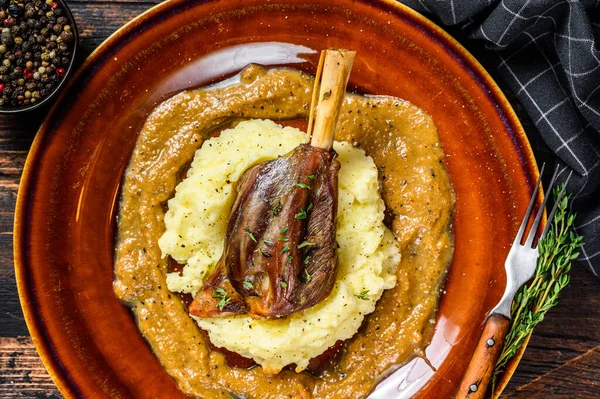 Stew Lamb Shanks with mash potato on a plate. Black background. Top view.