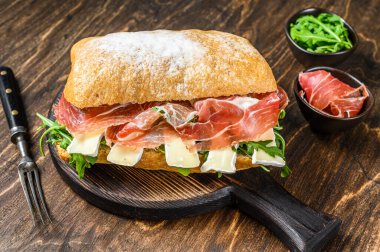 Jamon jambonlu sandviç, yanında roka ve peynirli peynirli ciabatta ekmeği. Ahşap arka plan. Üst görünüm.