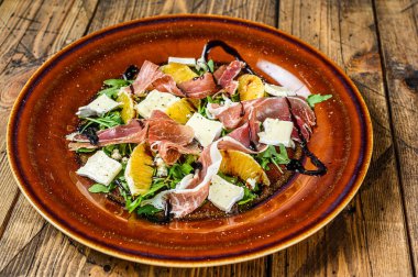Prosciutto parma jambonlu salata, parmesan peyniri, roka ve mandalina tabakta. Ahşap arka plan. Üst görünüm.
