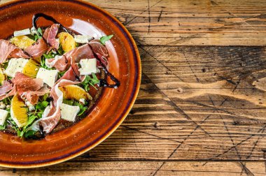 Prosciutto parma jambonlu salata, parmesan peyniri, roka ve mandalina tabakta. Ahşap arka plan. Üst Manzara. Boşluğu kopyala.