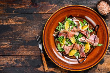 Jambonlu salata, parmesan peyniri, roka ve mandalina. Karanlık ahşap arka plan. Üst Manzara. Boşluğu kopyala.