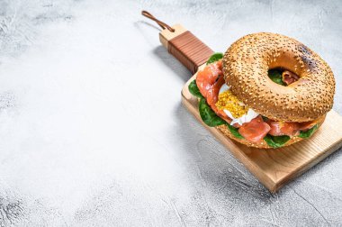 Somonlu bagel sandviç, krem peynir, ıspanak ve yumurta. Gri arka plan. Üst Manzara. Boşluğu kopyala.
