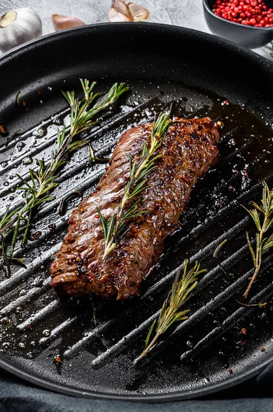 Cooked top blade, Denver steak in a pan. Marble meat beef. Gray background. Top view.