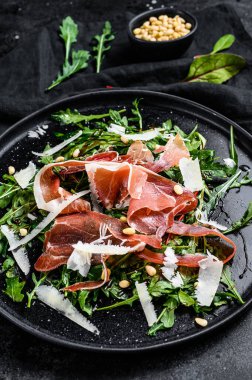 Parmalı salata, jambon, roka ve parmesan peyniri. Siyah arkaplan, üst görünüm