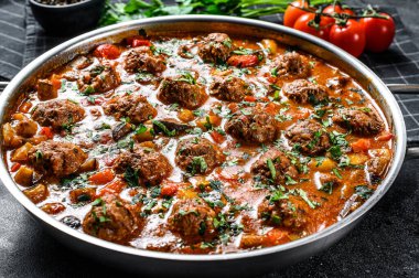 Domates soslu köfte ve tavada sebze. Siyah arka plan. Üst görünüm.