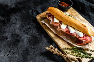 Jamon jambonlu sandviç, paleta iberica, kesim tahtasında Camembert peyniri. Siyah arkaplan, üst görünüm, metin için boşluk.