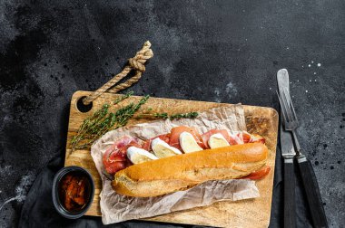 Jambonlu sandviç, dilimleme tahtasındaki peynirli peynirli sandviç. Siyah arkaplan, üst görünüm, metin için boşluk.
