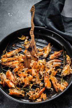 Arta kalan karidesler, tavada karidesler. Yiyecekler soyuldu, kafaların ayrıntıları verildi. Siyah arka plan. Üst görünüm.