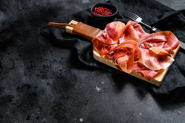 İspanyol jamonu Serrano, jambon. Siyah arkaplan, üst görünüm, metin için boşluk.