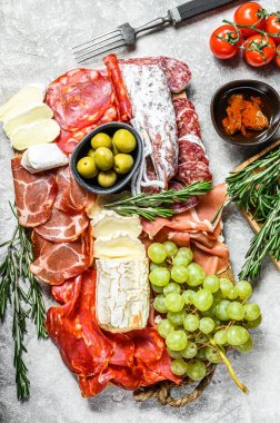 Üzümlü soğuk et, prosciutto, jambon, kurutulmuş et, sucuklu salam, fuet, camembert ve keçi peyniri. Gri arka plan. Üst görünüm.