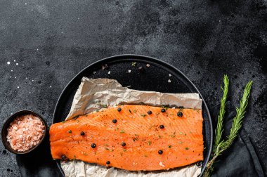 Taze somon fileto, tuz, bitki ve baharatlı. Siyah arka plan. Üst Manzara. Boşluğu kopyala.