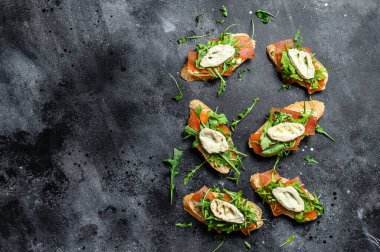 Keçi peynirli bruschetta, roka ve armut reçeli. Siyah arka plan. Üst Manzara. Boşluğu kopyala.