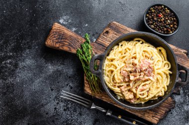 Pastırmalı makarna ve tavada parmesan. Siyah arka plan. Üst Manzara. Boşluğu kopyala.