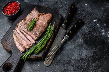 Kesme tahtasının üzerinde ızgara biftek ve pirzola. Siyah arka plan. Üst Manzara. Boşluğu kopyala.