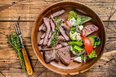 Ahşap tabakta biftek ve sebze salatası ile ızgara biftek. Ahşap arka plan. Üst görünüm.