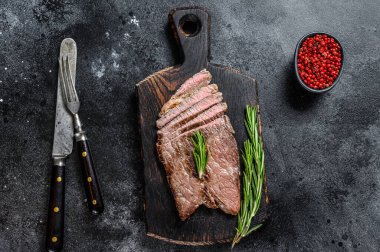 Kesme tahtasının üzerinde ızgara biftek ve pirzola. Siyah arka plan. Üst görünüm.