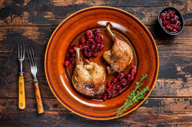 Kızarmış Noel ördeği bacakları ve kranberrie sosu. Koyu ahşap arka plan. en üstteki görünüm.