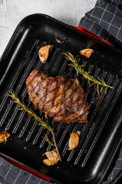 Izgara tavada ızgara demir biftek, mermer biftek. Gri arka plan. Üst görünüm.