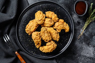 Siyah tabakta kızarmış tavuk kanadı. Siyah arka plan. Üst görünüm.