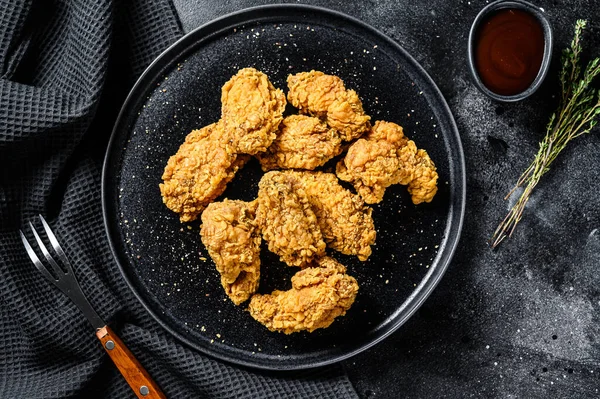 Siyah tabakta kızarmış tavuk kanadı. Siyah arka plan. Üst görünüm.