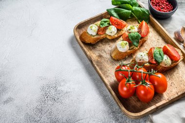 Domates, mozzarella peyniri ve fesleğen. İtalyan aperatifi ya da aperatifi, antipasto. gri arka plan. Üst Manzara. Boşluğu kopyala.