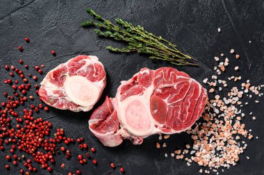 Çiğ taze ossobuco con ve şifalı otlar. Osso Buco eti. Siyah arka plan. Üst görünüm.