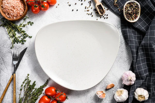 Taze çiğ sebze ve sebzelerin ortasında beyaz boş bir tabak. Sağlıklı, temiz yemek, vejetaryen, diyet yemek konsepti. Beyaz arka plan. Üst Manzara. Boşluğu kopyala.