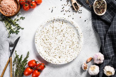 Taze çiğ sebze ve sebzelerin ortasında beyaz boş bir tabak. Sağlıklı, temiz yemek, vejetaryen, diyet yemek konsepti. Beyaz arka plan. Üst Manzara. Boşluğu kopyala.