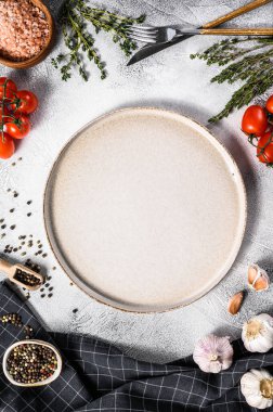 Taze çiğ sebze ve sebzelerin ortasında beyaz boş bir tabak. Sağlıklı, temiz yemek, vejetaryen, diyet yemek konsepti. Beyaz arka plan. Üst Manzara. Boşluğu kopyala.