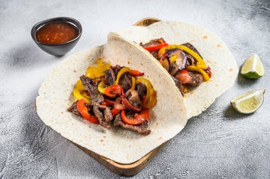 Et şeritli Fajitalar, renkli dolmalık biber ve soğan, tortilla ve salsa ile servis edilir. Beyaz arka plan. Üst görünüm.