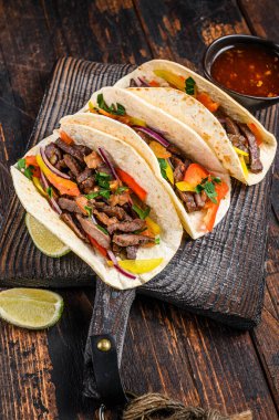 Domuz eti, soğan, domates, tatlı biber ve salsa soslu taco kabuğu. Meksika yemeği. Koyu ahşap arka plan. Üst görünüm.