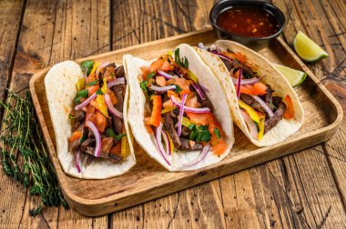 Biftek, soğan, domates, tatlı biber ve salsa soslu taco. Meksika yemeği. Ahşap arka plan. Üst görünüm.