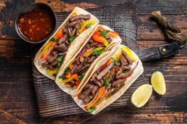 Domuz eti, soğan, domates, tatlı biber ve salsa soslu taco kabuğu. Meksika yemeği. Koyu ahşap arka plan. Üst görünüm.