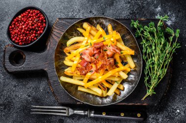 Erimiş çedar peyniri ve pastırmalı lezzetli patates kızartması. Siyah arka plan. Üst görünüm.