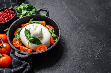Burrata mozzarella, vişneli domates ve fesleğenli Caprese salatası. Siyah arka plan. Üst Manzara. Boşluğu kopyala.