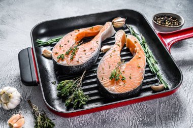 Biberiyeli somon bifteği ve tavada biber. Çiğ organik balık. Gri arka plan. Üst görünüm.