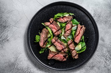 Ispanaklı biftek salatası, roka ve dilimlenmiş biftek. Gri arka plan. Üst görünüm.